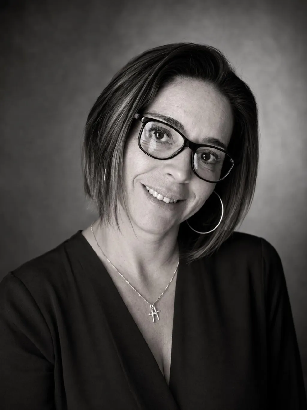 Portrait en noir et blanc d’Émilie, cheffe et gérante du restaurant, souriante et portant des lunettes