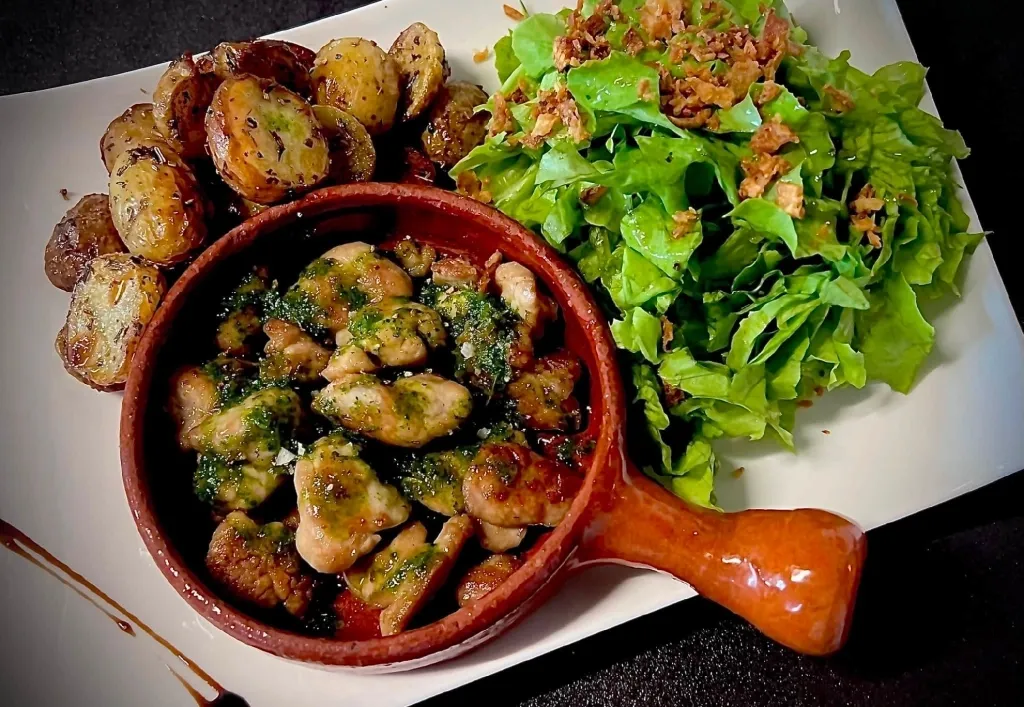 Ris d’agneau persillés dans un poêlon en terre, avec pommes de terre grenailles et salade verte