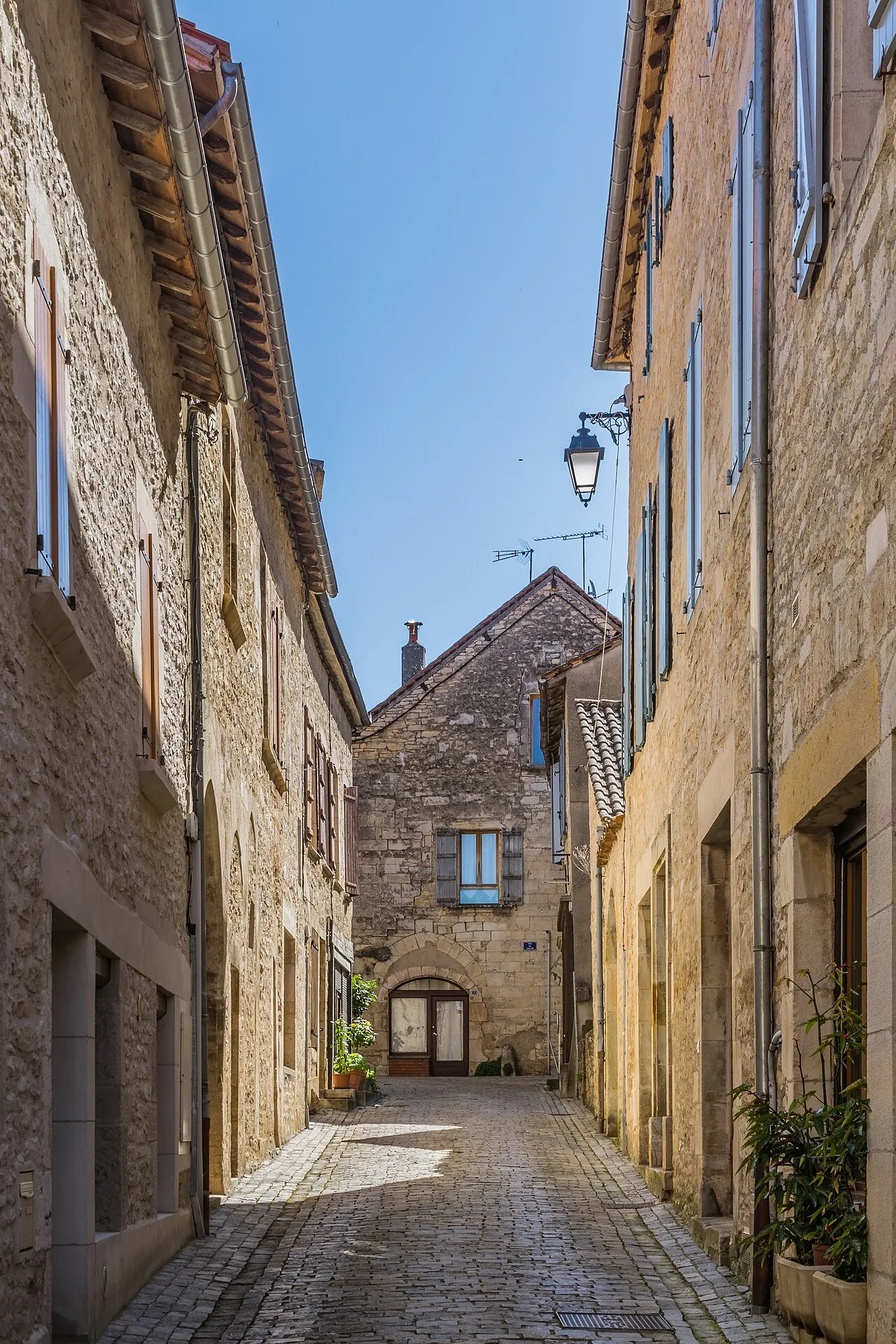 Ruelle pavée bordée de maisons en pierre dorée à Villeneuve-d’Aveyron