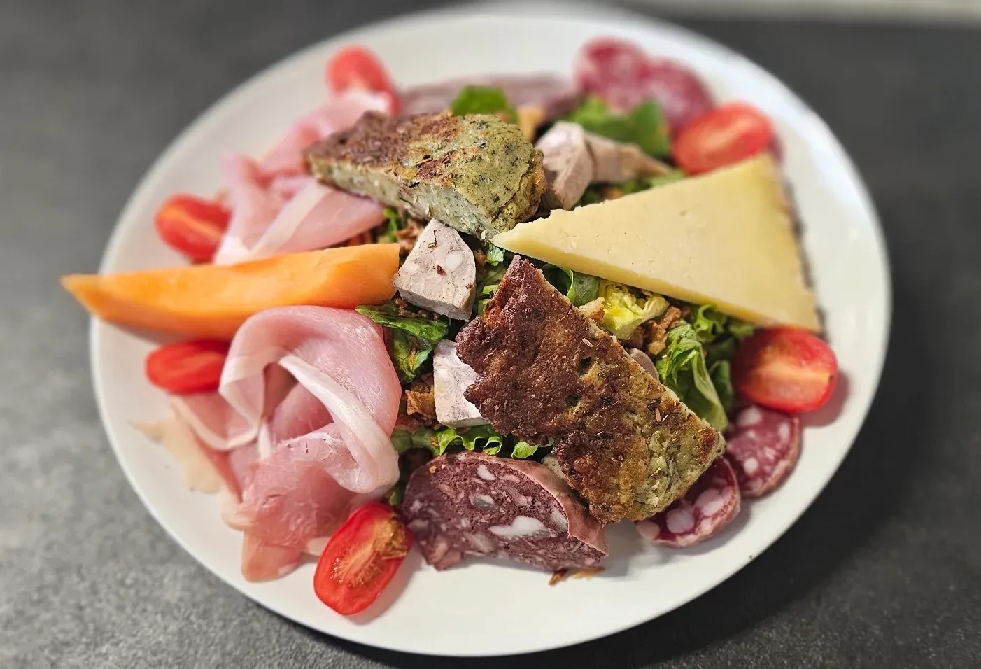 Assiette de salade du Terroir avec jambon cru, saucisson, farçous, fromage, melon et tomates cerises